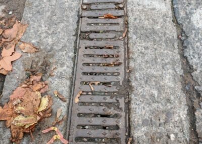 Leaves and debris visible around a surface drainage channel at a commercial site in Glasgow