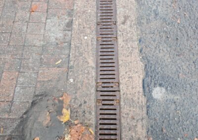 Cleaned drainage channel running along the entrance between paving and the road